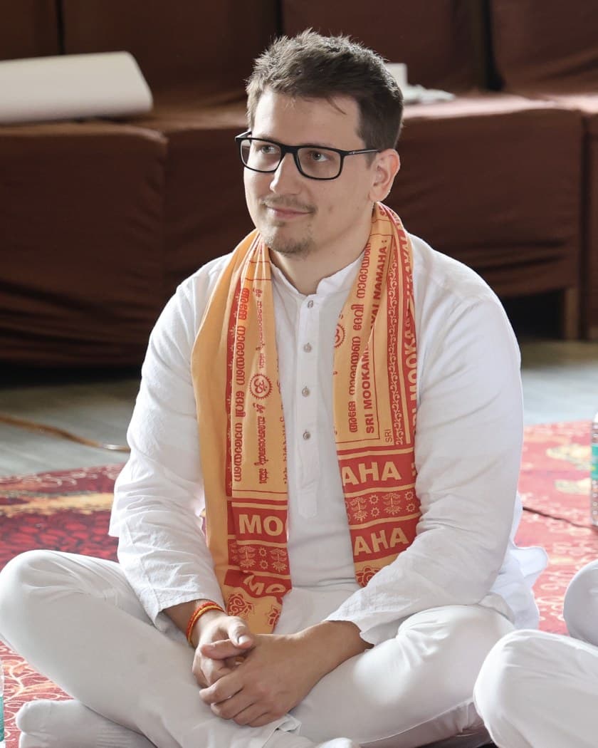 Horváth Marcell in white, sitting cross-legged on a carpet